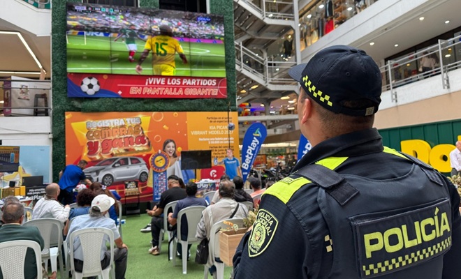 un policía, varias sillas, una pantalla y varios ciudadanos 