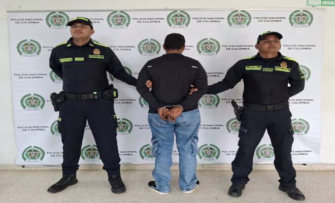 Dos uniformados custodian a un hombre se&ntilde;alado por presunto tr&aacute;fico de moneda falsificada.
