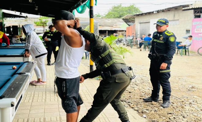 un uniformado realizando registro a un ciudadano  en un billar del sector