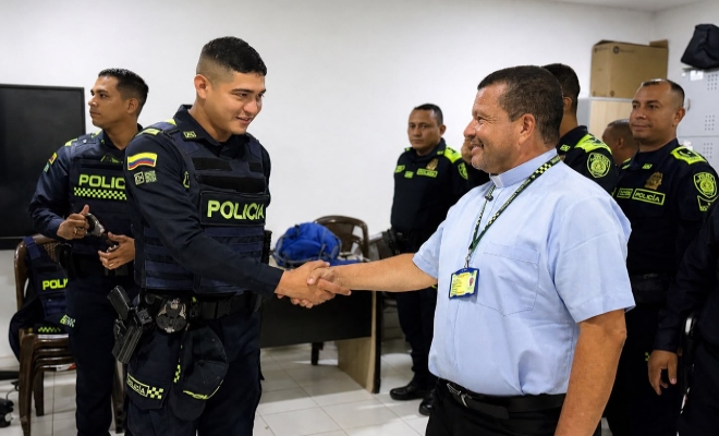 Funcionario policial saludando de mano al señor sacerdote con varios uniformados al fondo