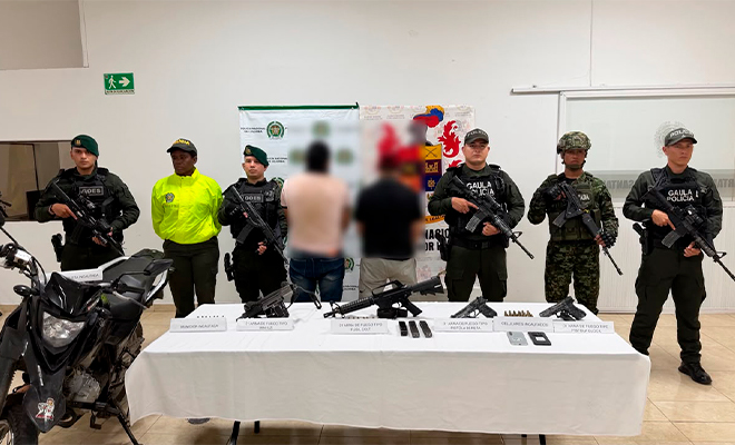 Captura en flagrancia de dos presuntos integrantes de la estructura criminal Autodefensas Conquistadoras de la Sierra escoltados por uniformados de la SIJIN y el Ejercito Nacional de Colombia y mesa con los elementos incautados
