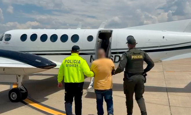 Dos policías llevan a un capturado para subirlo a un avión