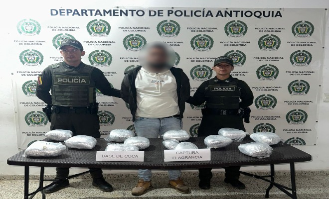 Dos Policías con un capturado y droga incautada encima de una mesa