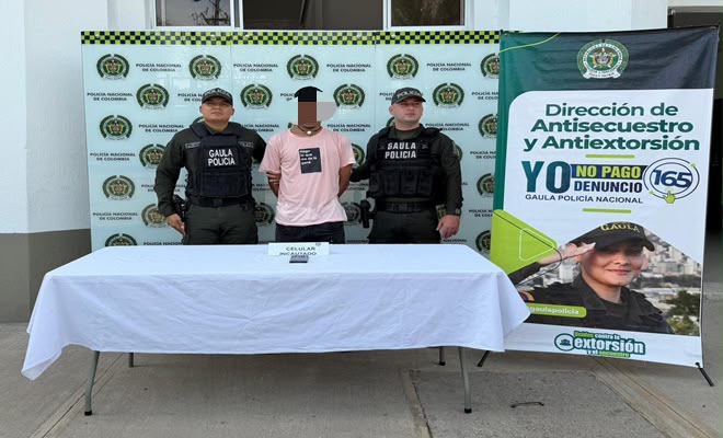 Una persona de sexo masculino capturada por el delito de extorsi&oacute;n, acompa&ntilde;ado de dos uniformados de la Polic&iacute;a Nacional brindando seguridad.
