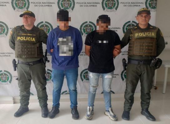 un policía al izquierda, dos capturados y un policía a la derecha 