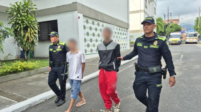 Dos polic&iacute;as conducen a dos capturados por el delito de hurto.
