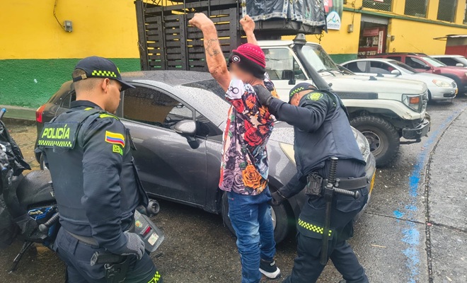Dos uniformados de la Polic&iacute;a est&aacute;n realizando un registro   a un hombre que tiene los brazos levantados contra un veh&iacute;culo gris