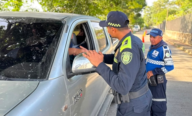 Funcionario policial saludando de mano a un ciudadano en un vehículo junto a funcionario de transito municipal 