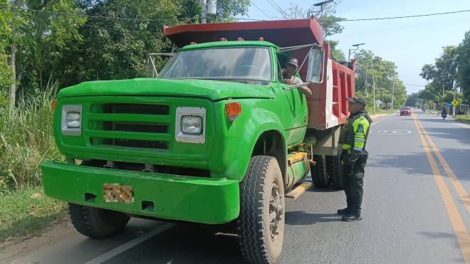 Funcionario policial de transito y transporte realizando consulta de antecedente y verificación de documento a un ciudadano en una volqueta 