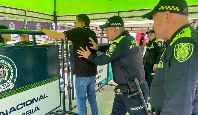 Policía realizando actividad de registro personal a un votante en el filtro de seguridad.