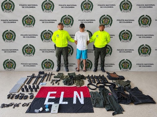 Dos policías custodiando un capturado y material incautado