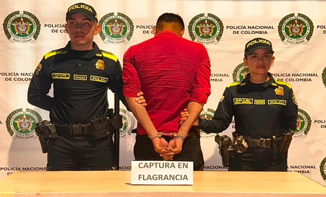 Dos polic&iacute;as custodiando el sujeto capturado frente al backing
