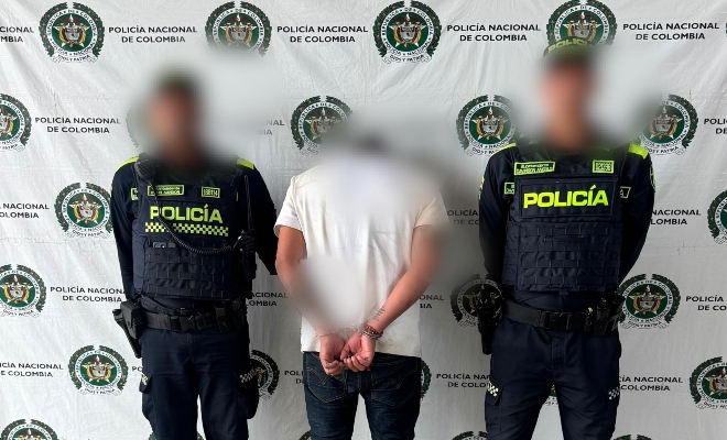 Dos funcionarios policiales con un ciudadano capturado, con pend&oacute;n institucional al fondo