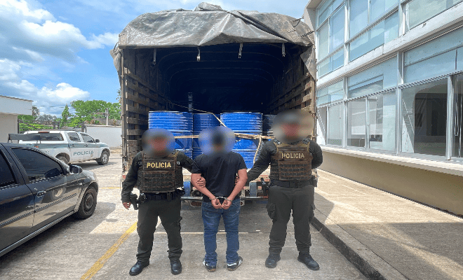 Un cami&oacute;n, y frente a &eacute;l dos polic&iacute;as junto a un hombre se&ntilde;alado de transportar sustancias ilegales