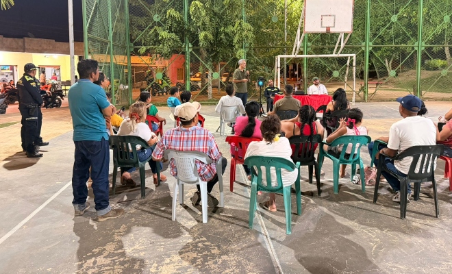 Funcionarios de policía y grupo de ciudadanos en un encuentro comunitario en el sector 20 de Julio del barrio Mocarí