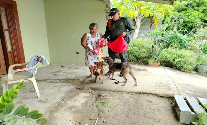 un uniformado realizando entrega de alimentos para mascotas a una ciudadana