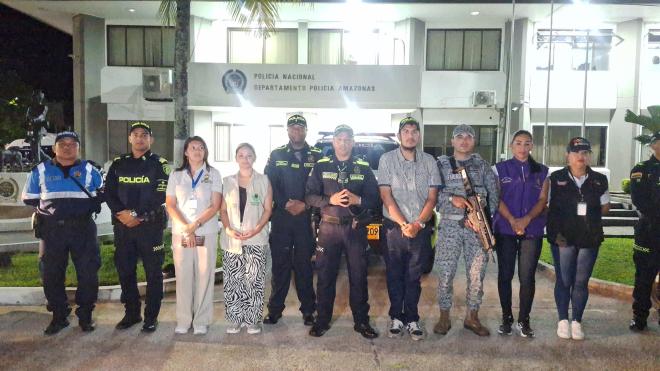 Tres polic&iacute;as y un miembro de la Fuerza A&eacute;rea de Colombia de pie acompa&ntilde;ados por funcionarios con camisas de distintos colores