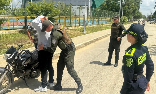 Un polic&iacute;a registrando a un ciudadano y dos polic&iacute;as prestando seguridad 