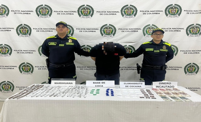 Dos uniformados con una persona capturada por el delito de tr&aacute;fico, fabricaci&oacute;n o porte de estupefacientes los cuales se muestran encima de una mesa