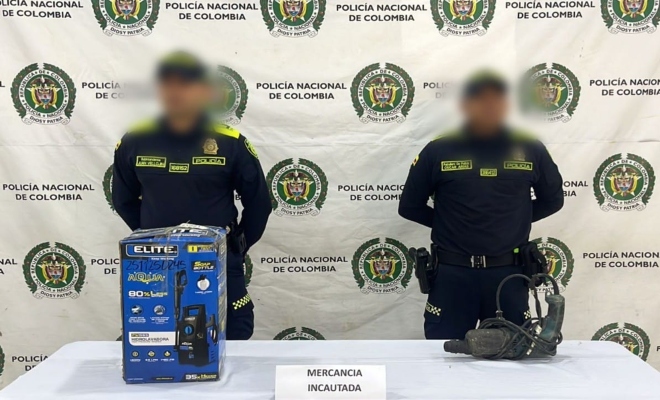 dos policias y en mesa mercancia incautada 