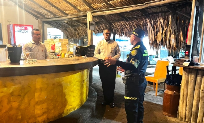 Funcionario policial brindando recomendaciones a dos ciudadanos comerciantes 