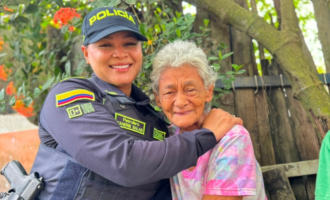 Funcionaria policial en compa&ntilde;&iacute;a de una adulta mayor sonriendo