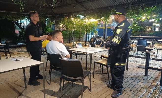 Funcionario policial brindando recomendaciones a dos ciudadanos en establecimiento público 
