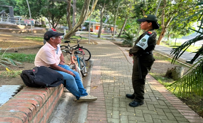una  uniformada de la policía nacional  y un ciudadano en el parque principal de la ciudad de montería 