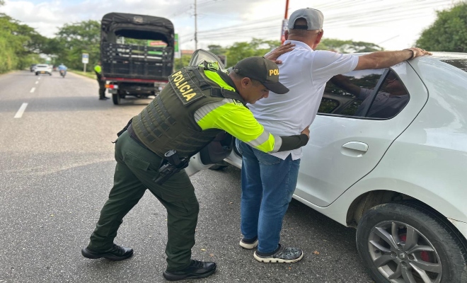 un uniformado de  la policía nacional realizando un registro a un ciudadano en vía publica 