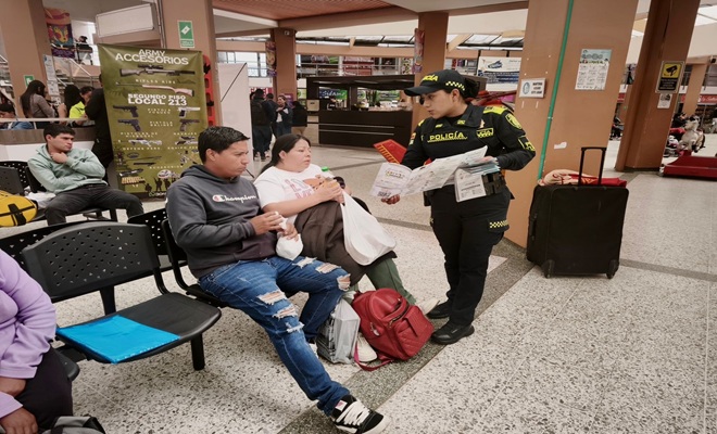 dos ciudadanos sentados en la terminal de transporte de Pasto y un funcionario policial 