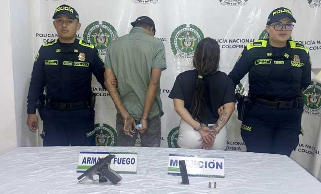 Hombre y mujer capturados en media de dos policías, en frente arma de fuego incautada