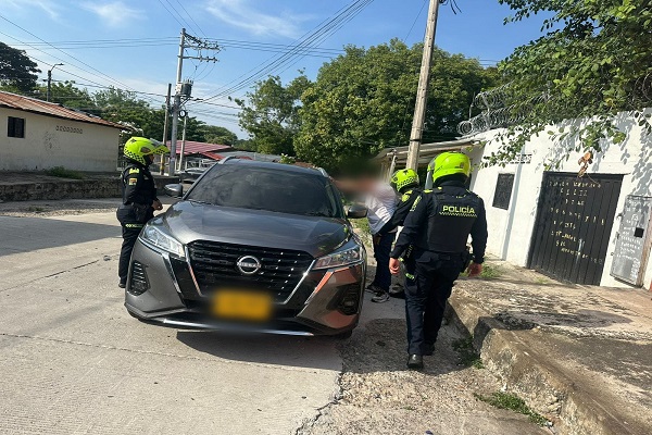 Un Policía realizando registro a persona a ciudadano y dos Policías prestando seguridad