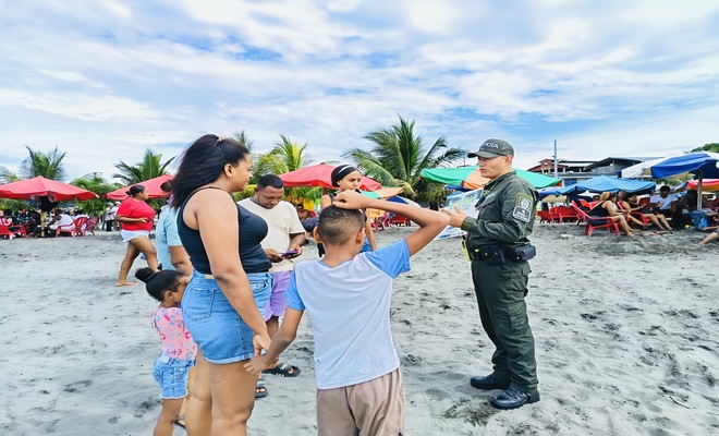 Un uniformado con ciudadanos en las playas del Morro realizando una socialización 