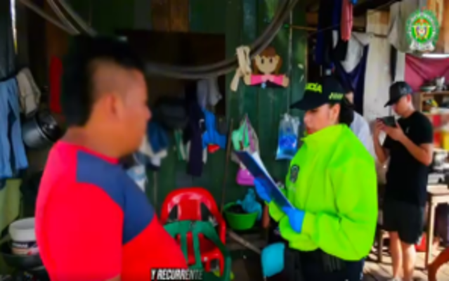 uniformada con chaqueta verde clara sostiene unos documentos delante de un hombre con camisa roja el cual es el capturado