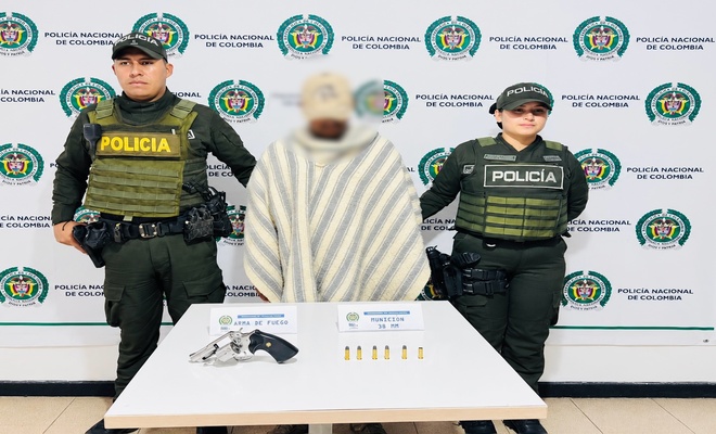 Un ciudadano capturado con dos policías en cada lado respectivamente y un arma de fuego incautada 