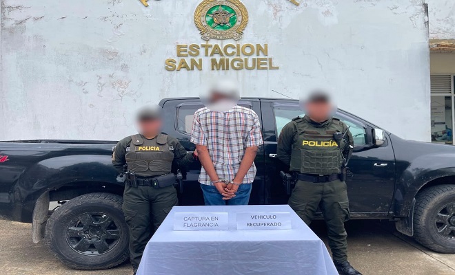 Dos polic&iacute;as, una Camioneta de fondo, al frente dos personas con la persona capturada 