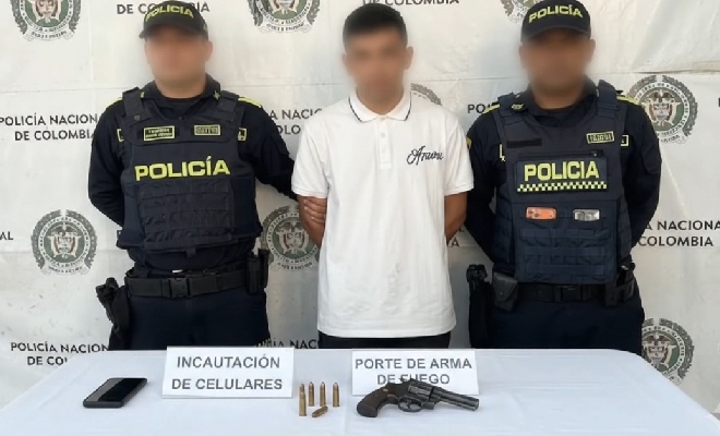 Dos policías custodian el capturado y el arma incautada