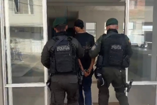 Hombre capturado de camiseta negra en medio de dos policías
