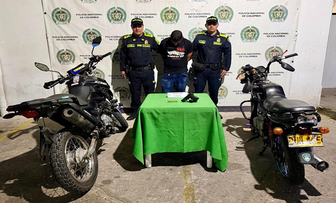 Dos Policías prestando seguridad a una persona capturada por el delito de hurto en Barrancabermeja, dos motocicletas y un arma de fuego incautada. 