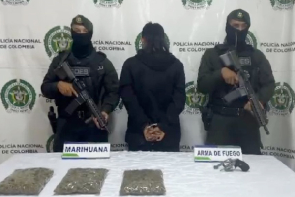 Hombre capturado en medio de dos policías, en frente elementos incautados