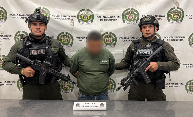 Una persona capturada que se encuentra esposado y a su lado dos policías del GOES