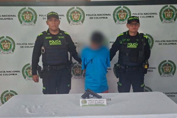 Hombre capturado de camiseta celeste en medio de dos Policías