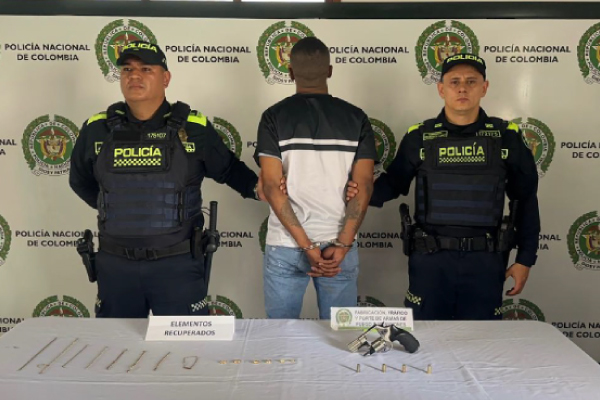 Hombre capturado en medio de dos policías, en frente elementos incautados