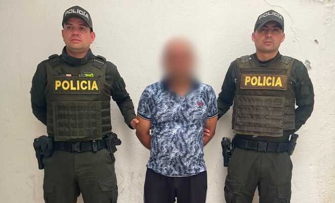 Un ciudadano capturado quien se encuentra esposado con dos polic&iacute;as en cada lado respectivamente 