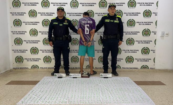 Hombre capturado en medio de dos polic&iacute;as, en frente elementos incautados