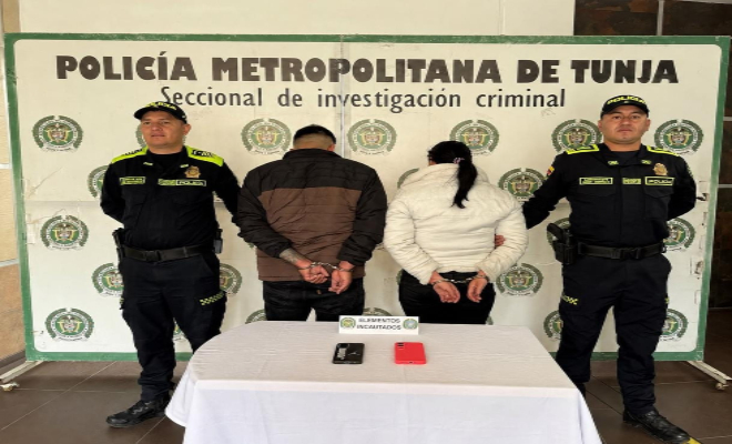 dos polic&iacute;as en cada lado y dos personas capturadas una mesa con elementos incautados