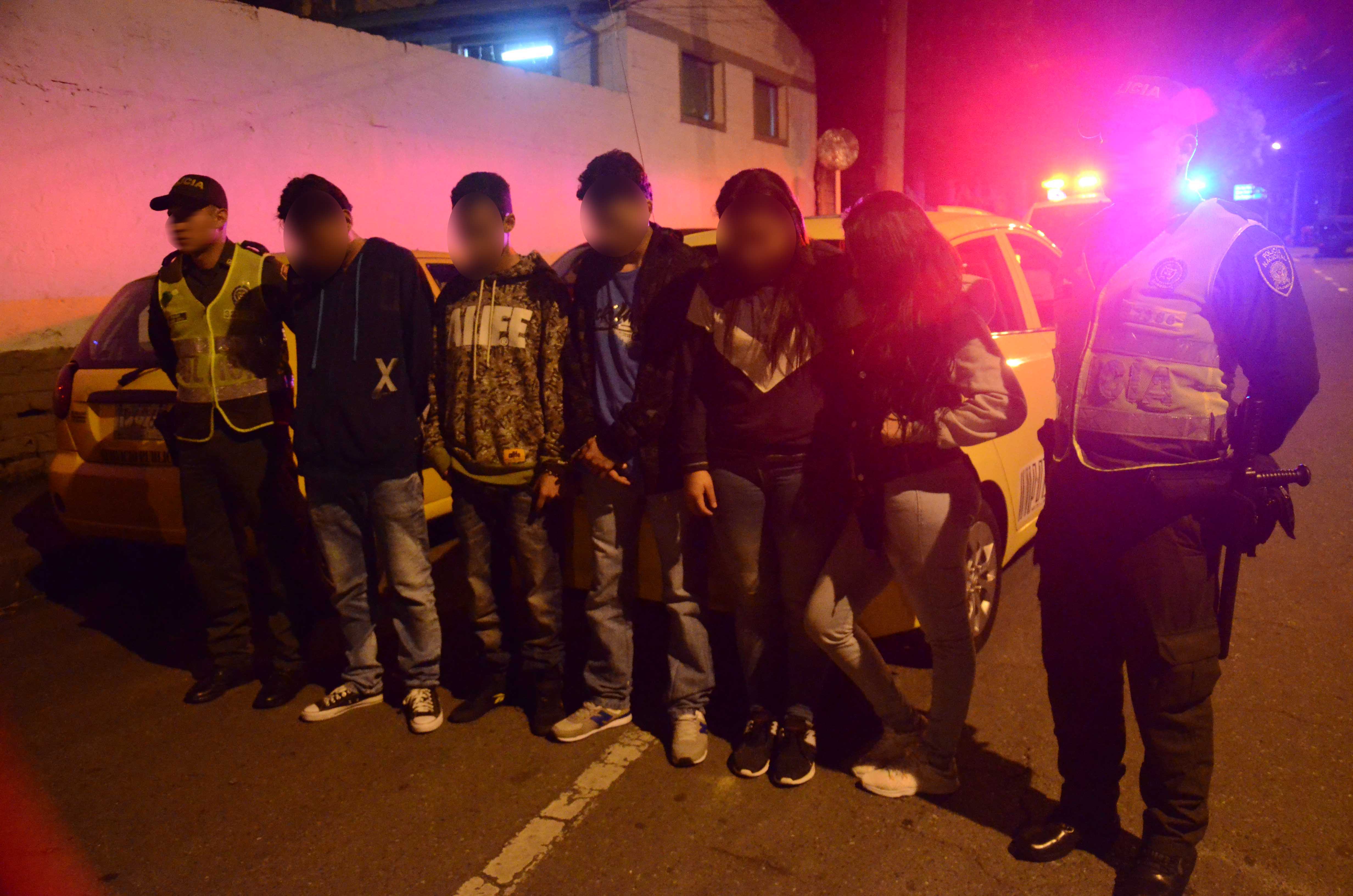 Dos policías custodian a cinco personas capturadas en Medellín