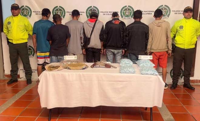 Hombres capturados en medio de dos Policías, en frente elementos incautados