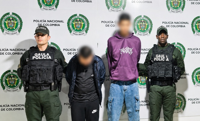 Dos personas esposadas quienes se encuentran capturados y dos policías del GAULA en cada lado 