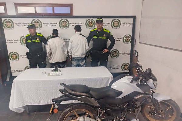 Dos hombres capturados en medio de dos policías, con arma de fuego y una motocicleta incautada